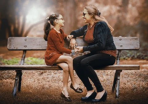 Mother and daughter sat on a park bench